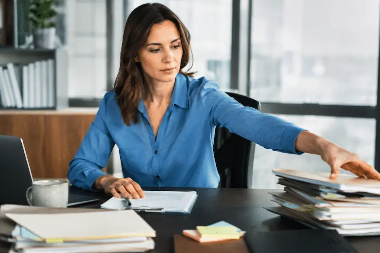 Une femme trie une pile de dossiers sur son bureau